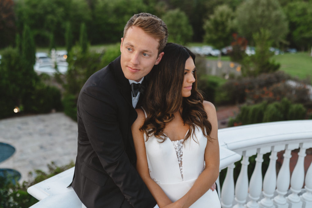Newly wed couple sitting on roof top wearing black tux and beautiful white wedding dress