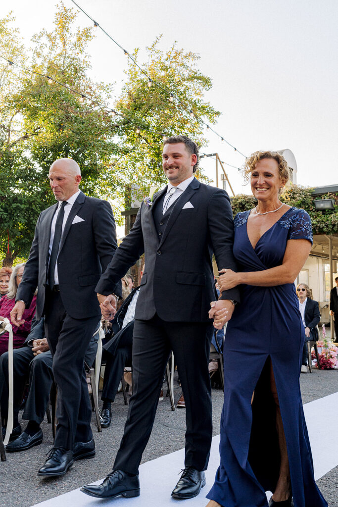 Groom being walked down the aisle by his parents