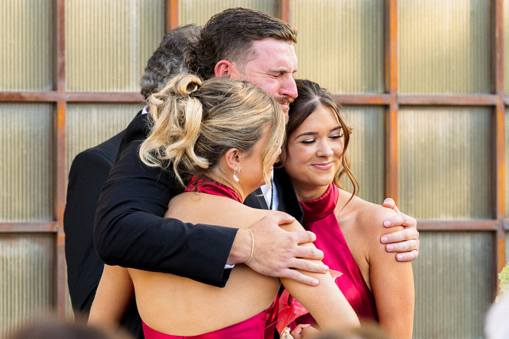 Groom hugging the brides sisters before seeing bride walk down the aisle